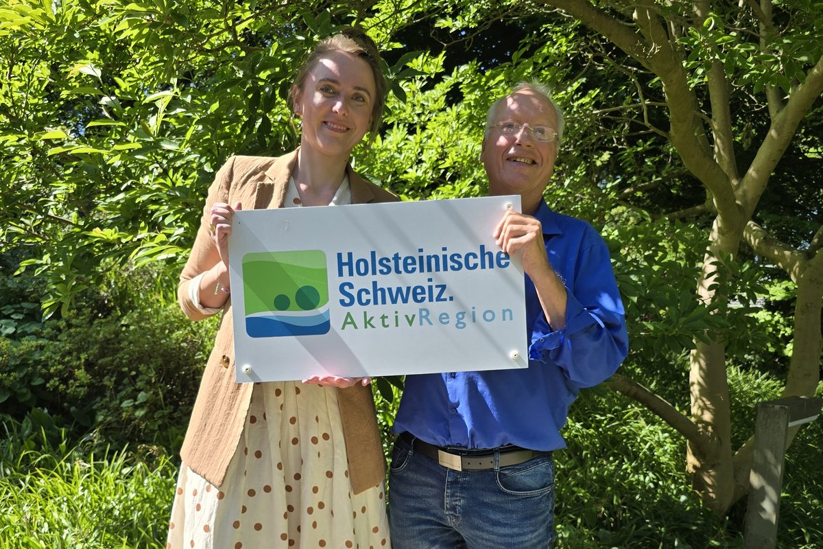 2 Mitarbeiter präsentieren das Logo der Holsteinischen Schweiz